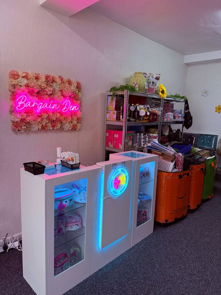 Pink neon Bargain Den sign on a flower wall inside the shop